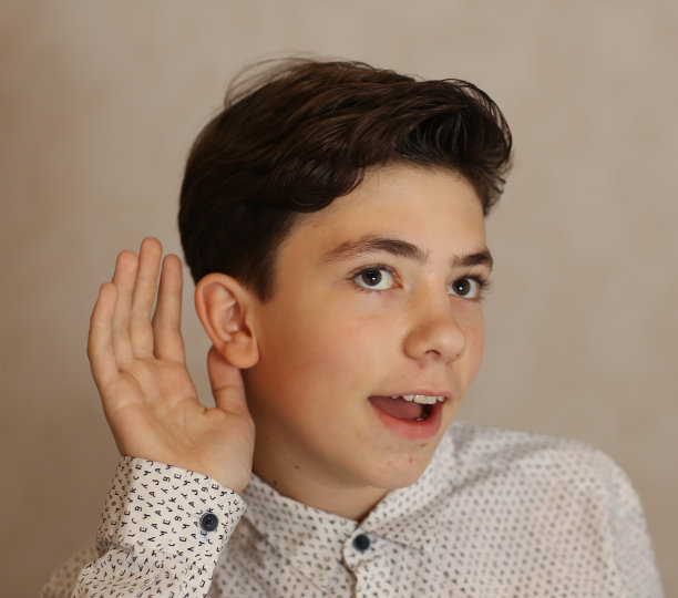 少年男孩用耳朵和手做一个听的手势图片下载