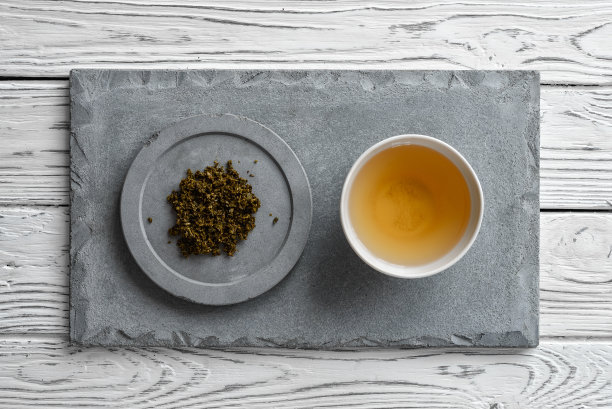 浅白色木质背景上的灰色混凝土板和一杯茶图片下载