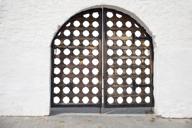 白色墙壁上的中世纪雕花大门。旧建筑的一个入口。图片下载