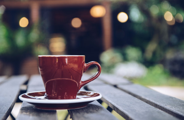 陶瓷咖啡杯放在木板桌上，背景是美丽的散景。图片下载