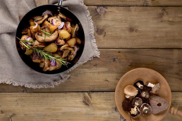 在一个黑色的铸铁平底锅里炸土豆，背景是木头。复古照片和乡村风格的餐巾。自由空间的文本，俯视图。图片下载