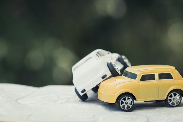汽车事故和汽车保险概念:两辆微型汽车在道路上碰撞碰撞，破玩具汽车在城市地图上，绿色背景。图片下载