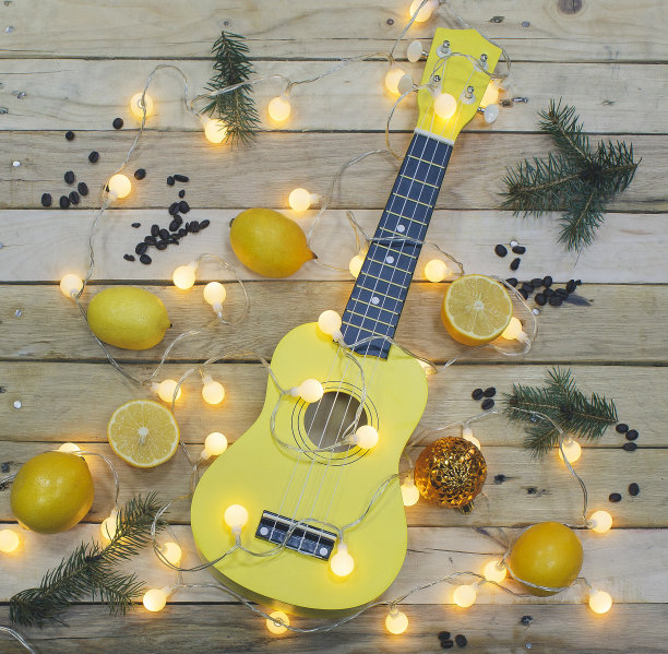 照片拍摄，俯视图黄色尤克里里和柠檬在木制背景。图片下载