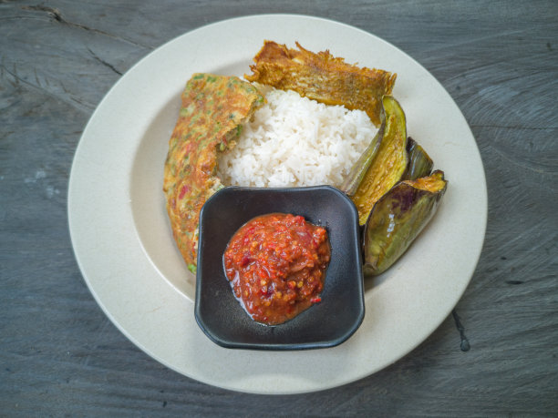 选择马来西亚人最喜欢的菜肴为午餐或晚餐。木桌上放着白米饭、虾酱、炸鱼、煎蛋和炒茄子。图片下载