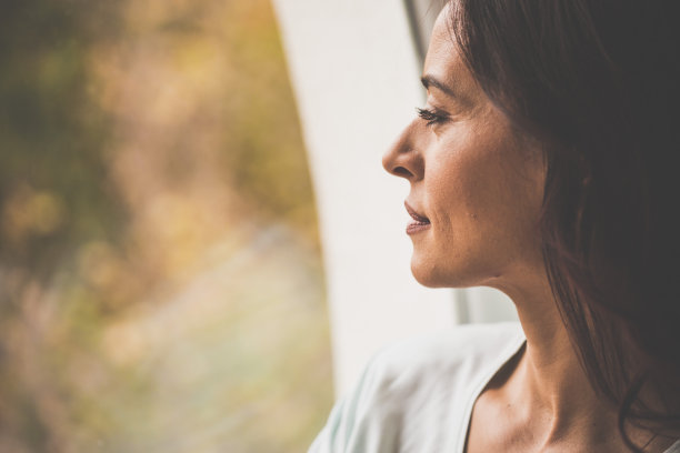 沉思的女人透过窗户看图片下载