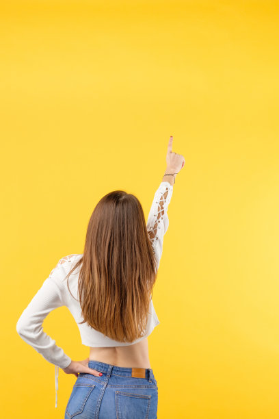 苗条的女人牛仔黄色背景指向上面图片下载
