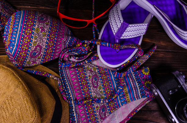 游泳衣，帽子，人字拖，太阳镜和旧相机放在木桌上。前视图。暑假的概念图片下载