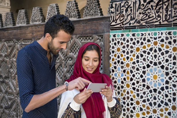 微笑的穆斯林夫妇看着手机图片下载