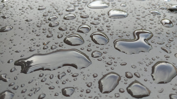 雨滴或水滴在引擎盖上的汽车。雨滴在汽车表面或铁表面流下。抽象背景和水纹理设计图片下载