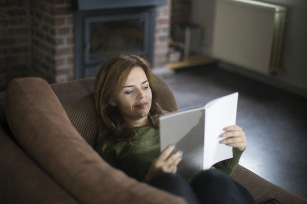年轻女子躺在床上看书图片下载