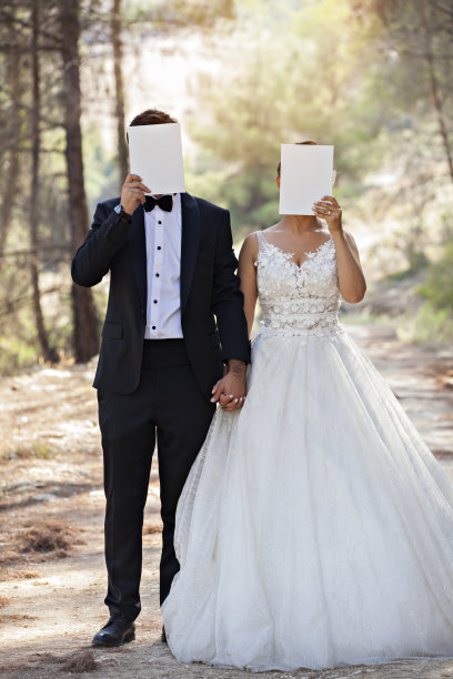 新婚夫妇用白纸遮住脸。图片下载