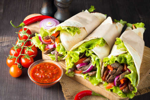 照片上的墨西哥三明治食物，玉米煎饼，菲希塔，玉米饼，玉米粉圆饼，牛肉，鸡肉，新鲜蔬菜在乡村的木制背景。快餐的概念。健康的午餐小吃。副本的空间。图片下载