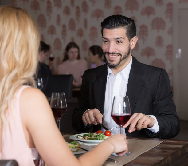 微笑的男人和女人在晚餐与葡萄酒图片下载
