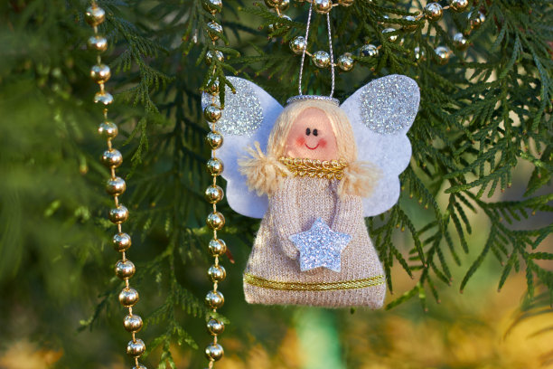 节日装饰。树枝上的圣诞天使。金珠子。手工圣诞树玩具。自然的户外照片。寒假。新年快乐，圣诞快乐。图片下载