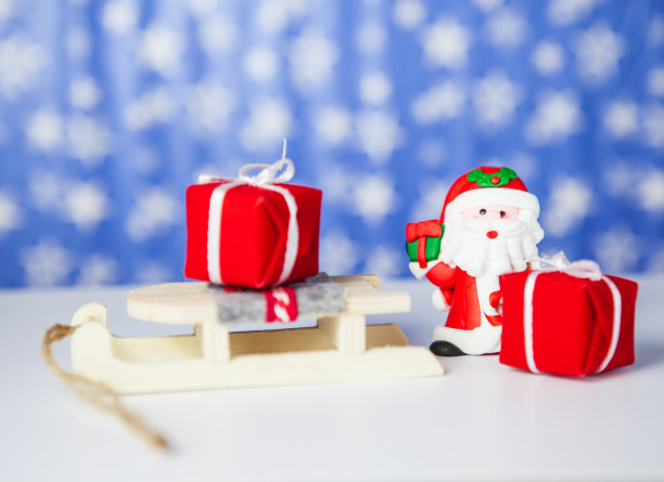 圣诞礼盒放在雪橇上的圣诞老人和圣诞老人，在蓝色背景上图片下载