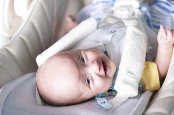 新生婴儿被固定在高脚椅上，用五点背带喂养。有选择性的重点图片下载