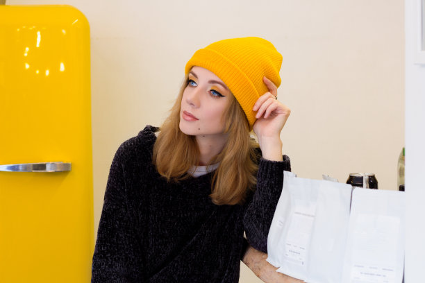 一个戴着黄色帽子的女人坐在咖啡店的一张桌子旁图片下载