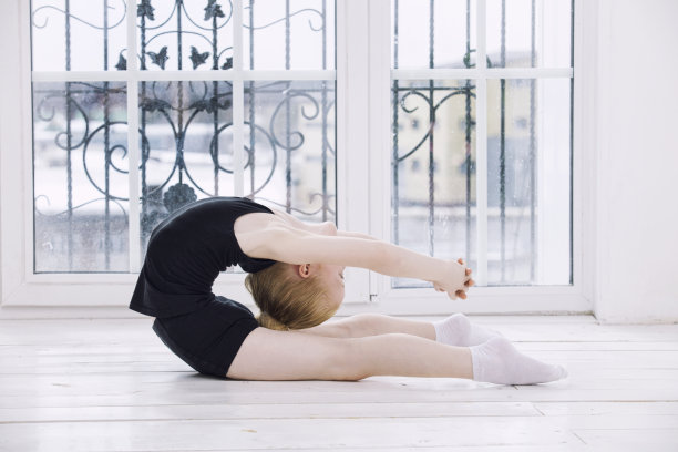 小女孩体操在一个明亮的房间里做伸展运动在一个快乐和可爱的窗户背景图片下载