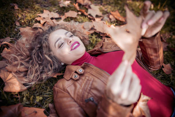 快乐的年轻女子在秋天的公园里放松图片下载