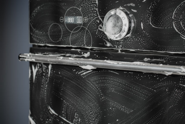 清洗在烹饪过程中获得的污染物表面，内置烤箱的黑色玻璃表面可以看到肥皂泡。图片下载