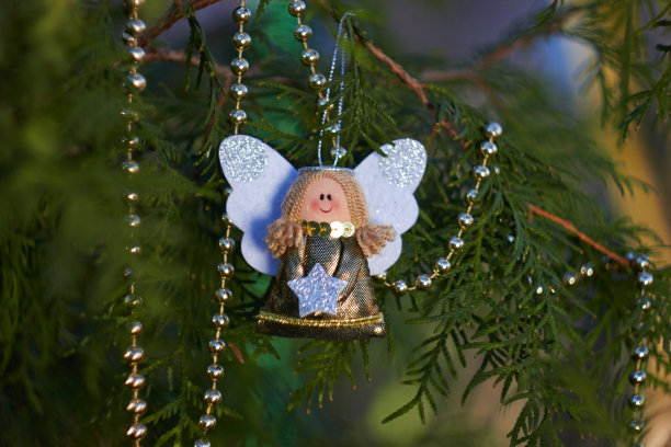 节日装饰。树枝上的圣诞天使。金珠子。手工圣诞树玩具。自然的户外照片。寒假。新年快乐，圣诞快乐。图片下载
