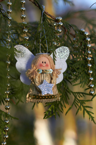 节日装饰。树枝上的圣诞天使。金珠子。手工圣诞树玩具。自然的户外照片。寒假。新年快乐，圣诞快乐。图片下载