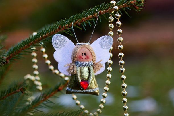 节日装饰。树枝上的圣诞天使。金珠子。手工圣诞树玩具。自然的户外照片。寒假。新年快乐，圣诞快乐。图片下载