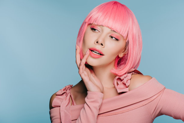 美丽性感的女孩手势和摆姿势在粉红色的假发孤立在蓝色图片下载