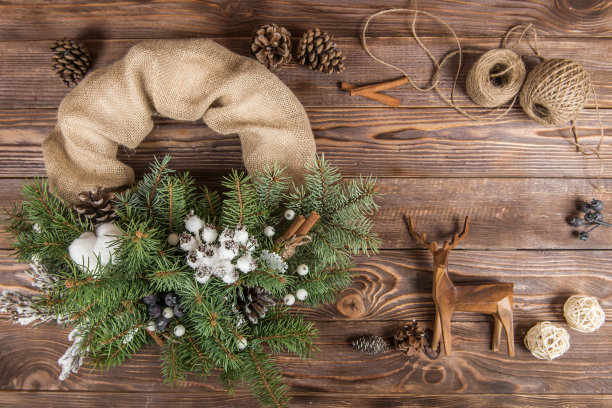 花环。圣诞冬季框架上的深色木制背景。冷杉球果和棉花。木制玩具鹿图片下载