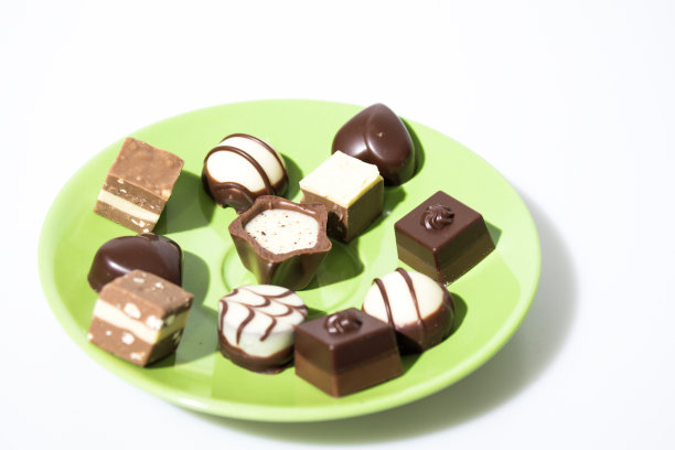 许多巧克力在一个绿色的盘子孤立在一个白色的背景组成图片下载
