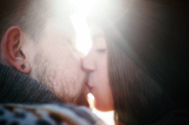 快乐的女孩在阳光下亲吻留着红胡子的男友图片下载