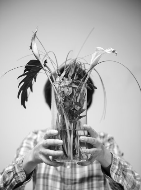 一个女人手里举着花瓶，花瓶上插着死去的植物图片下载