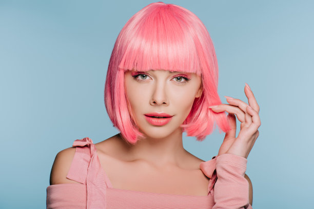 迷人的时尚女人手势和摆姿势在粉红色的假发孤立在蓝色图片下载