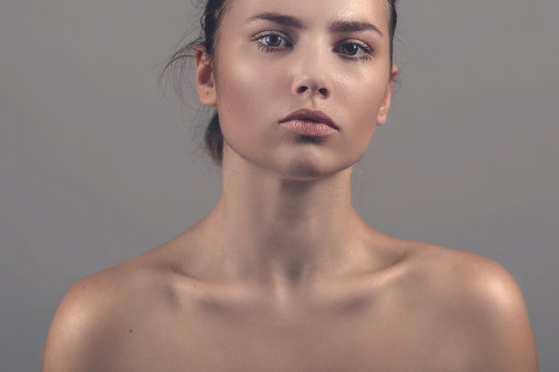 一个美丽的年轻女人的肖像特写在灰色的背景图片下载