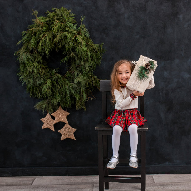 快乐微笑的女孩与圣诞礼物盒。图片下载