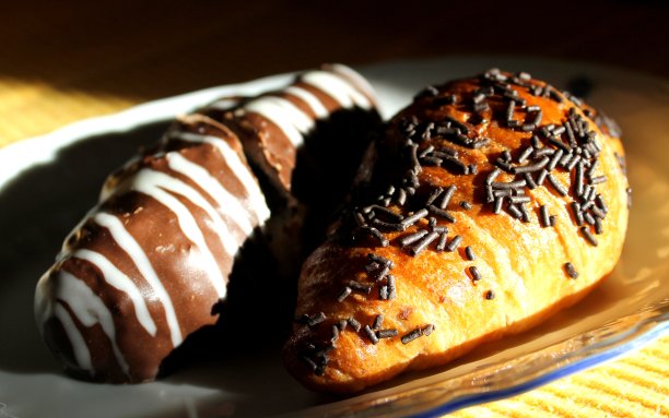 美味的羊角面包上有小巧克力滴和另一个羊角面包覆盖着巧克力图片下载