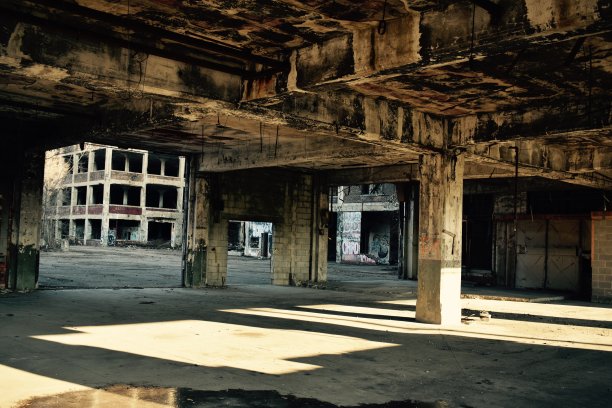 旧的，废弃的，由混凝土和钢铁建造的汽车工厂，由室外照明照明。图片下载