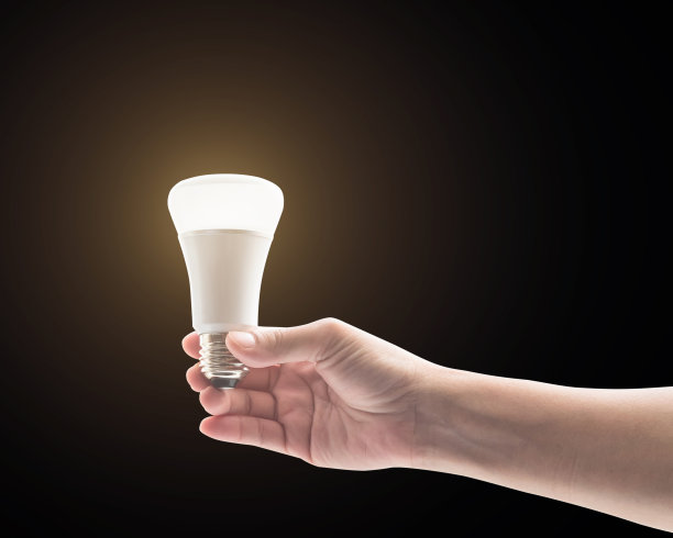 节能理念与女人的手握LED发光二极管灯泡隔离在黑色背景(裁剪路径)图片下载