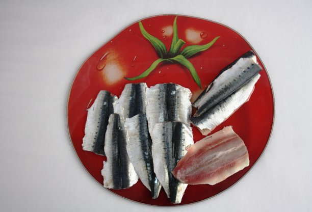 生沙丁鱼，在书中打开的盘子上有一个红色西红柿的图片图片下载