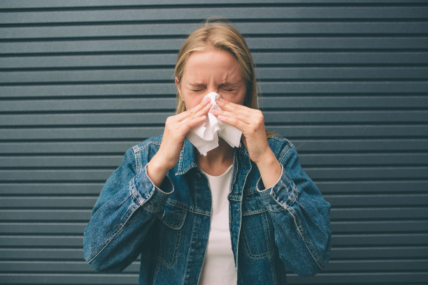 这是一个拿着手帕的年轻女子的照片。生病的女模特流鼻涕。图片下载