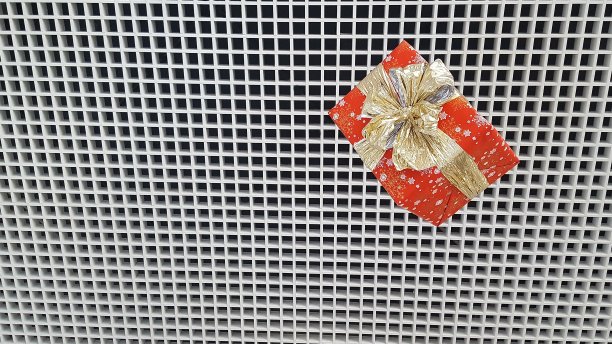 圣诞礼物在一个明亮的包装用一个美丽的弓在背景的格子与小牢房。新年假期的概念。图片下载