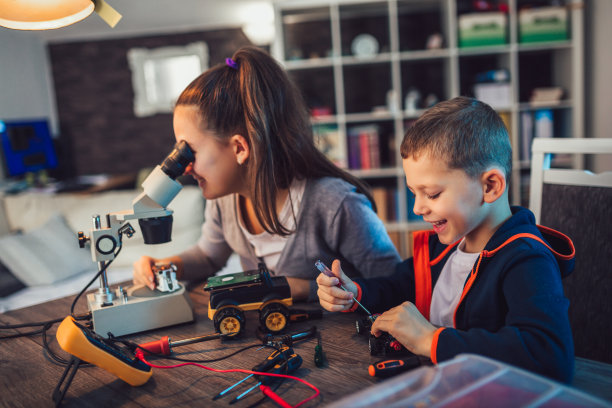 快乐微笑的男孩和女孩构建技术玩具。桌上满是技术玩具的细节图片下载