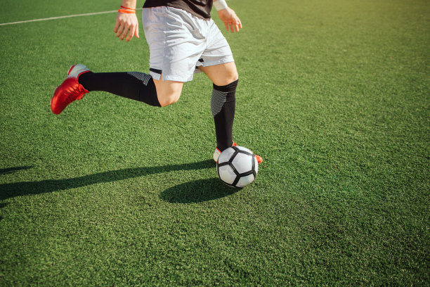 男人踢足球的照片。他要去踢球。他一个人在球场上踢球。外面阳光明媚。减少视图。图片下载