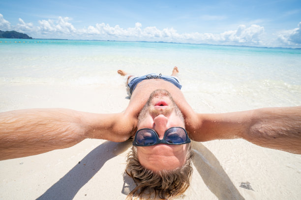 酷酷的年轻人在热带海滩上自拍颠倒享受假期图片下载