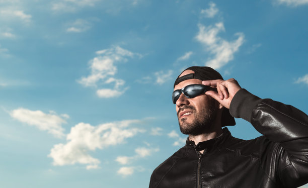 一个戴着眼镜和帽子、胡子拉碴的野蛮男人。他移开视线，傻笑着。图片下载