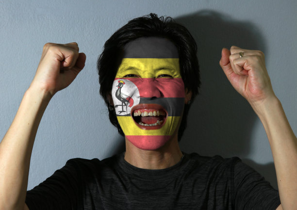 一幅欢快的男子肖像，灰色背景上画着乌干达国旗。图片下载
