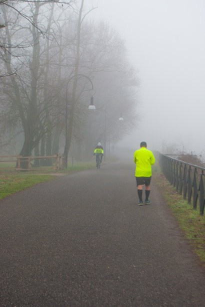 在大雾天穿着技术服的自行车和跑步者图片下载
