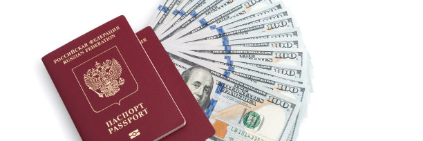 两本红色护照和一张白色背景的百元美钞。图片下载