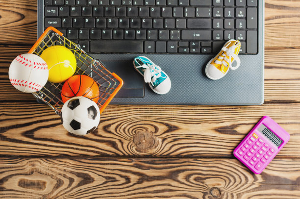 计算器在运动器材附近，在旧的脏的笔记本电脑上，在棕色的桌子上有拷贝空间。网上贸易的概念。俯视图图片下载