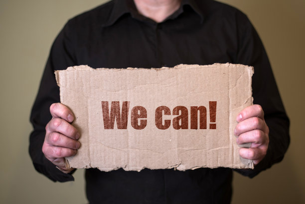 一个穿着黑衬衫的人拿着一块纸板上面写着我们可以图片下载